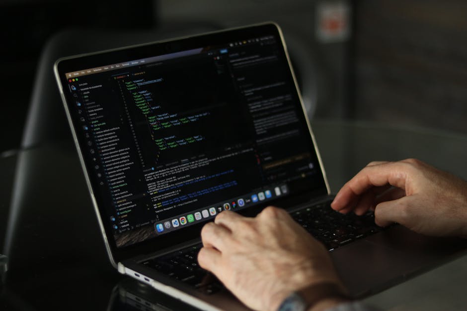 A close-up photograph of a computer screen displaying lines of HTML and code, with multicolored syntax highlighting in red, blue, yellow, and white text on a dark background. The HTML code includes ta
